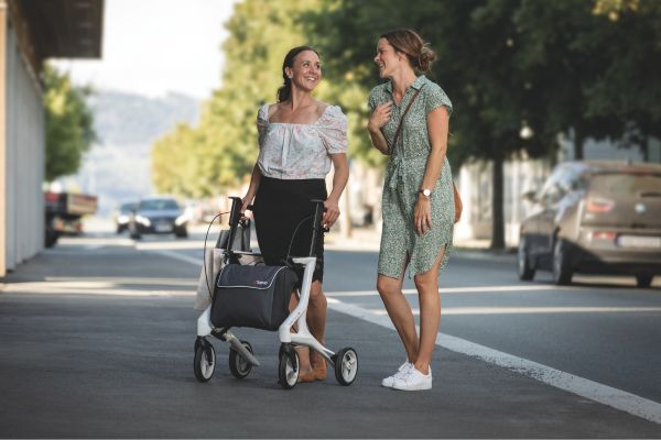 Zwei Frauen im Gespräch, eine Frau hat einen Rollator.